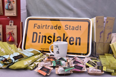 Ortseingangsschild Fairtrade Stadt Dinslaken mit einer Produktauswahl aus Fairem Handel 