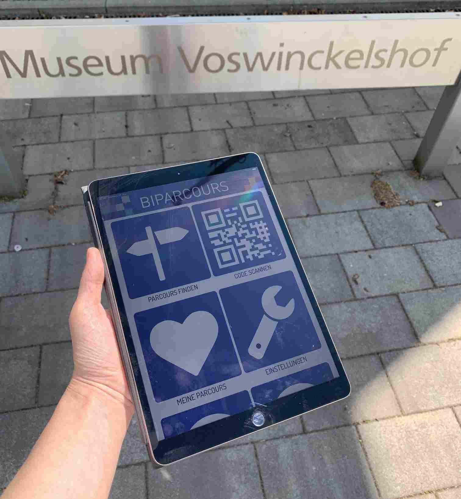 BIPARCOURS-Startseite auf einem iPad vor dem Eingangsschild zum Museum Voswinckelshof