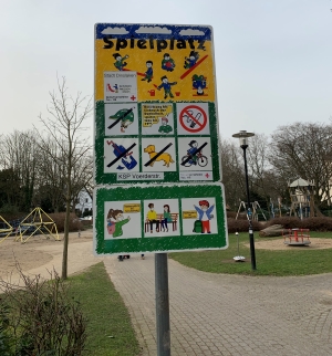 Spielplatzschild mit Maskenhinweis